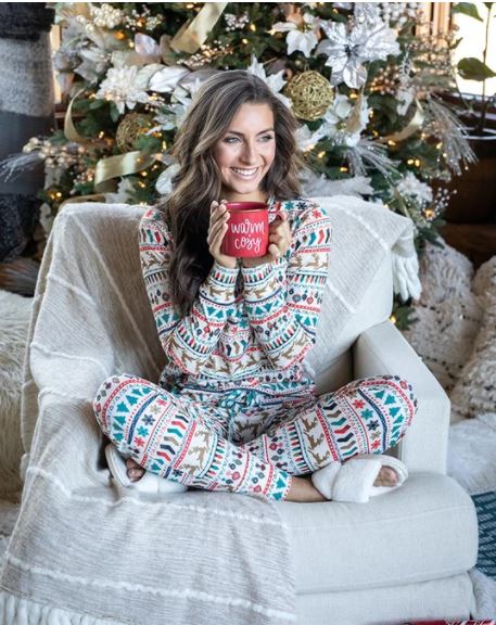 Women on Couch with Cozy Holiday Pajamas and Warm Beverage
