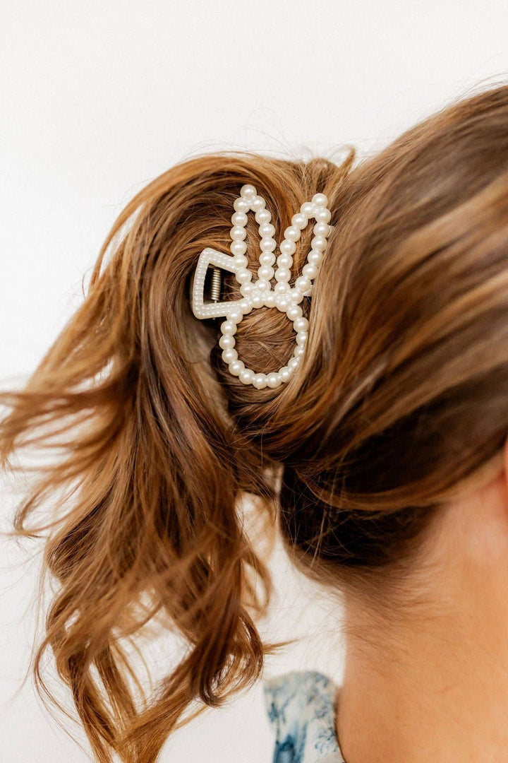 Close-up of pearl beaded bunny ear claw clip worn in a half-up hairstyle with wavy brown hair.
