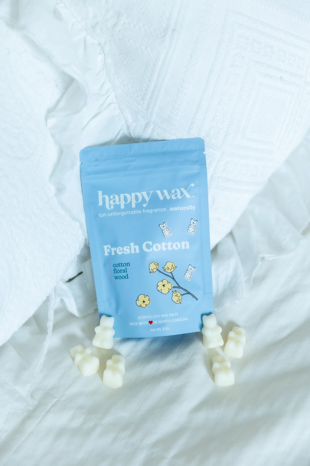 Happy Wax Fresh Cotton light blue pouch with cream bear-shaped wax melts on a rumpled white linen background.
