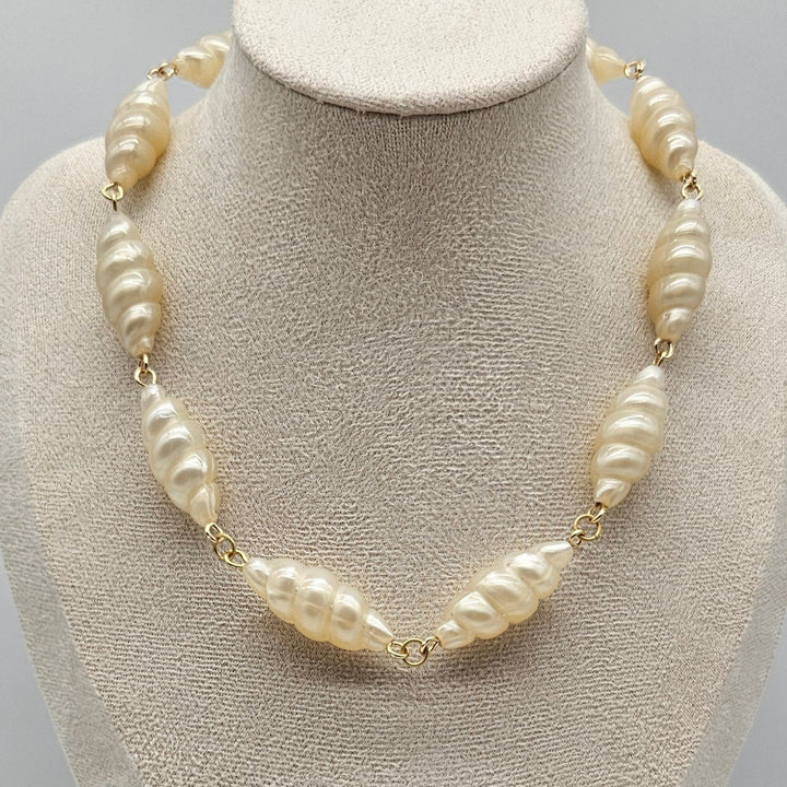 Lucite pearl necklace on a mannequin bust against a neutral background