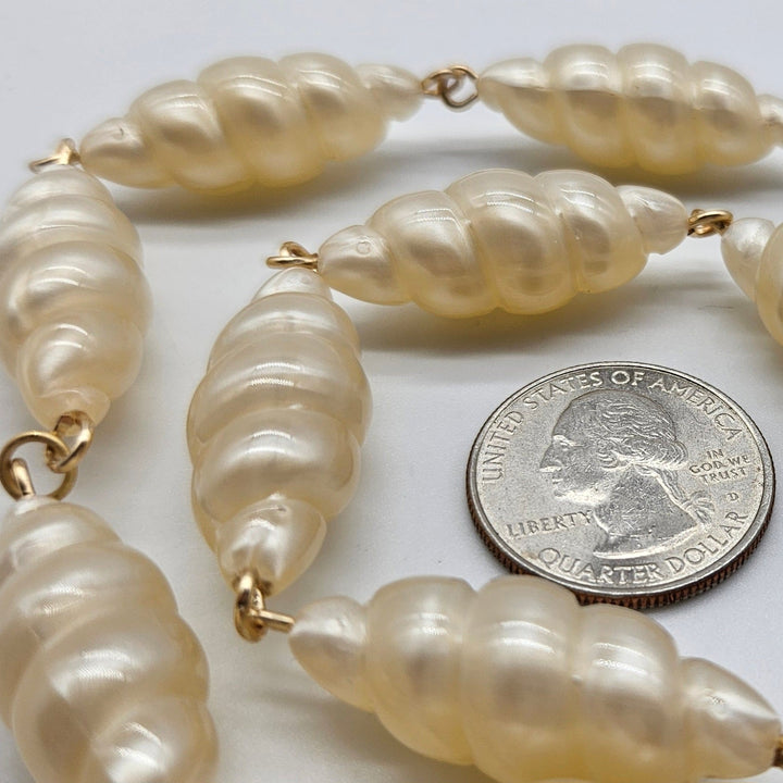 Lucite necklace with a quarter for scale on a white background