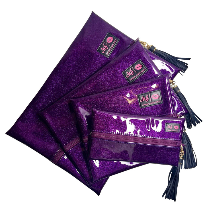 Makeup Junkie Bags deep purple glitter clear vinyl zip bags in four sizes fanned out with navy tassel zipper pulls and branded patches, front view on white background