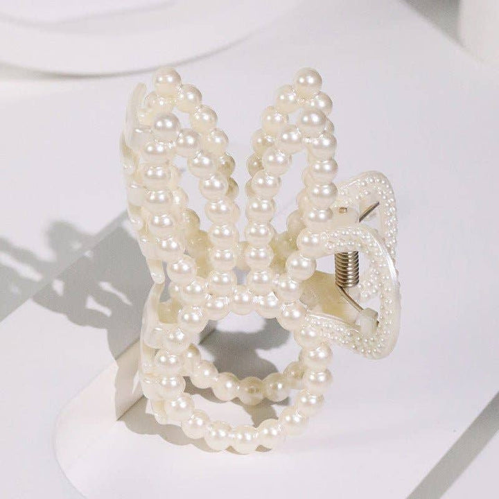 Pearl beaded bunny ear claw clip product shot on white surface showing side angle of bunny ear silhouette and spring claw mechanism.