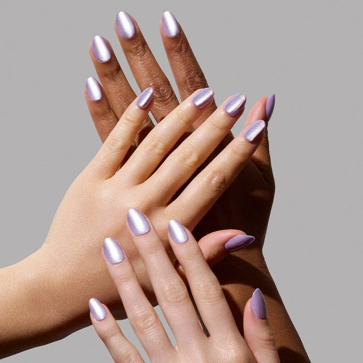 Three hands with different skin tones wearing Glamnetic Mermaid's Tail Press-On Nails in short oval shape with iridescent lavender chrome finish on a gray background