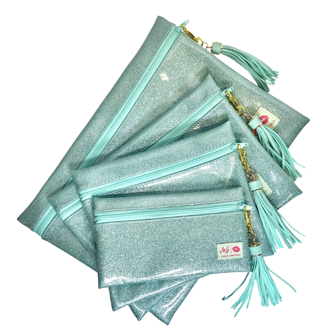 Makeup Junkie Bags mint glitter zip makeup bags in four sizes fanned out with mint tassel zipper pulls and branded patches, front view on white background