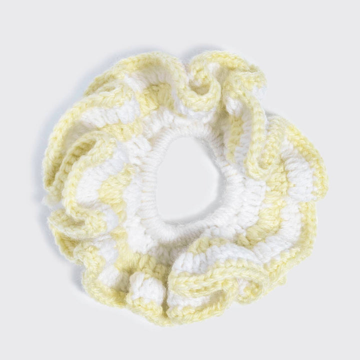 Flat lay top-down view of a butter yellow and white crochet scrunchie with a ruffled, wavy texture, on a white background.