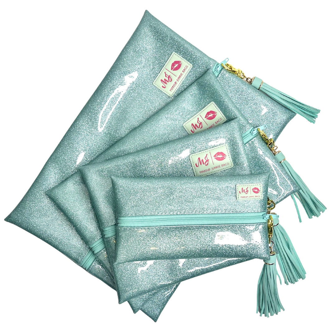 Makeup Junkie Bags mint glitter zip makeup bags in four sizes fanned flat showing branded patches and mint tassel zipper pulls, front view on white background