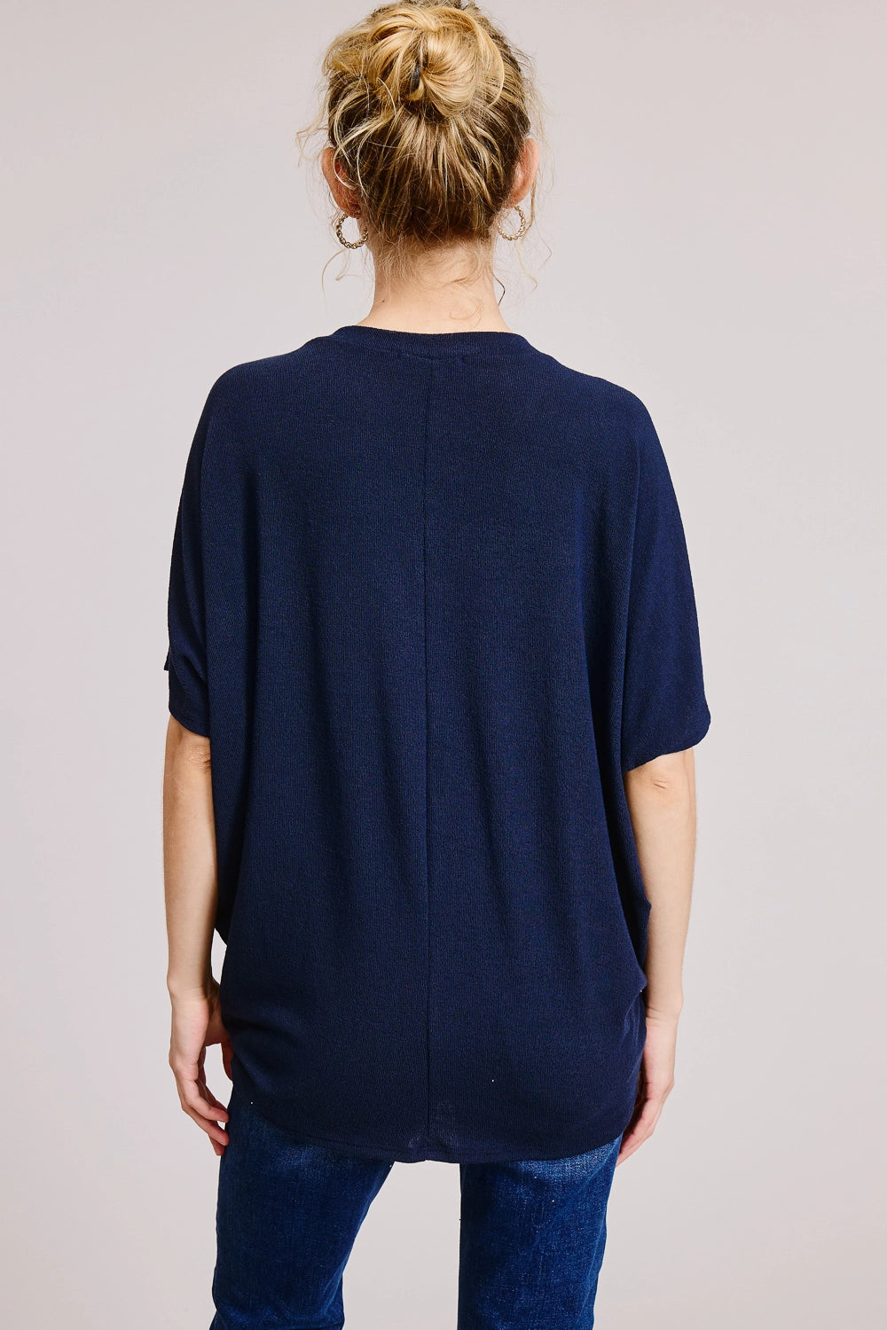 Back view of navy heathered V-neck oversized tee showing dolman sleeves, center back seam, and relaxed boxy fit, styled with dark wash straight-leg jeans.