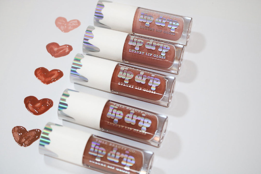 Five Lip Drip Luxury Lip Gloss tubes in nude to deep brown shades displayed with matching heart-shaped color swatches