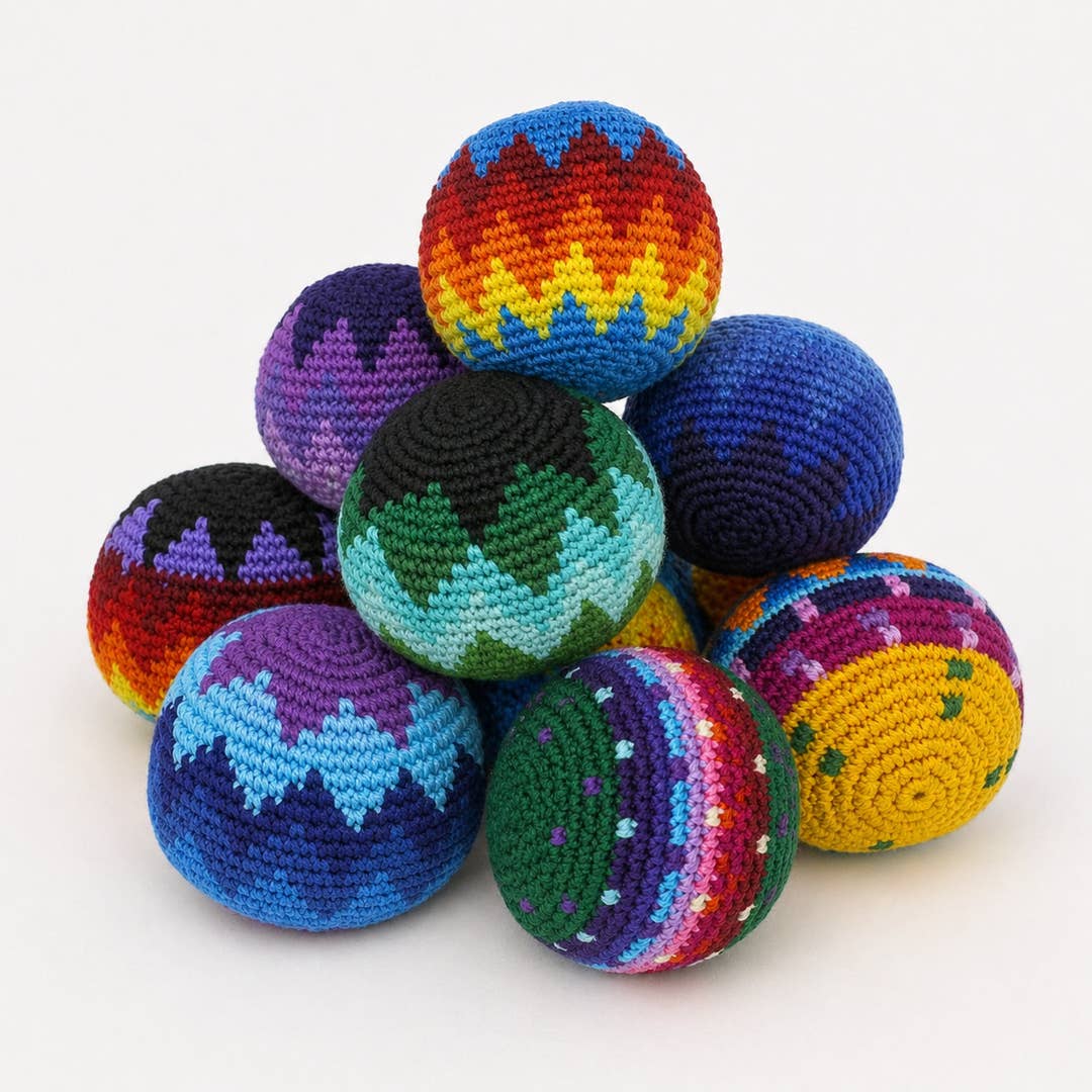 Assorted handmade crochet hacky sacks in multicolor zigzag, stripe, and geometric patterns stacked in a pyramid, front view on white background