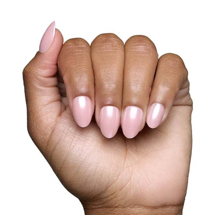 Close-up of blush pink short oval press-on nails worn on medium skin tone hand against white background
