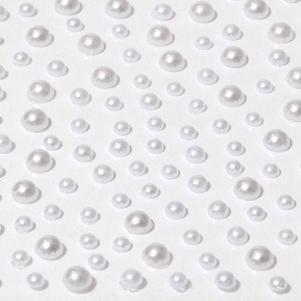 Close-up of Glamnetic white pearl nail decal stickers in assorted sizes on a white background