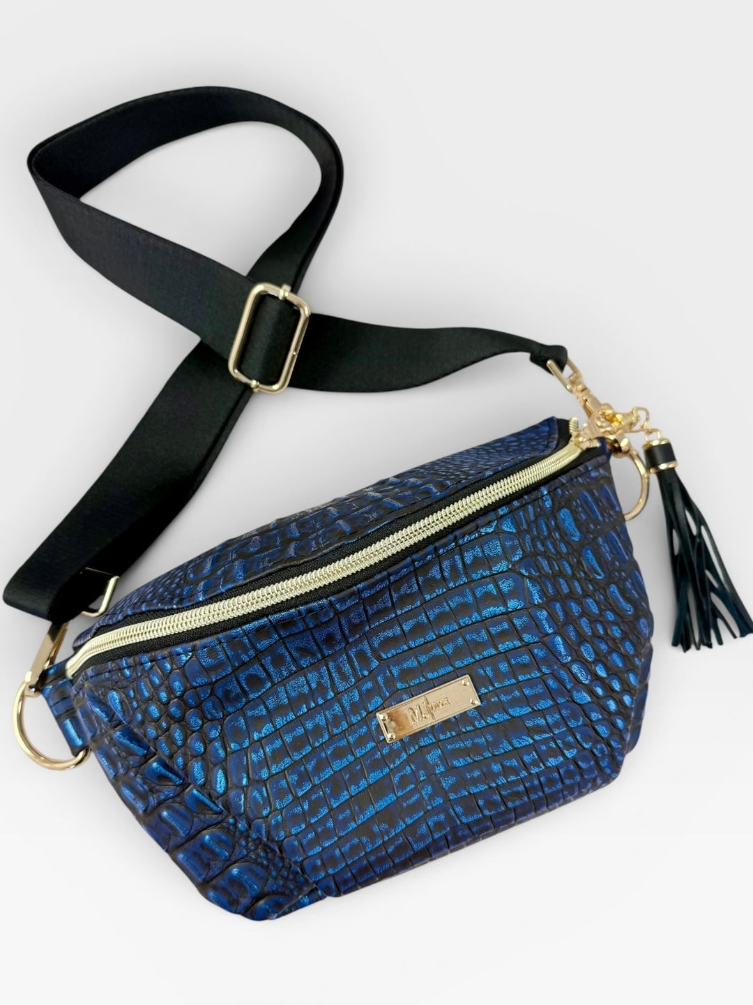 Blue metallic croc-embossed belt bag with gold zipper, black tassel, and wide black crossbody strap