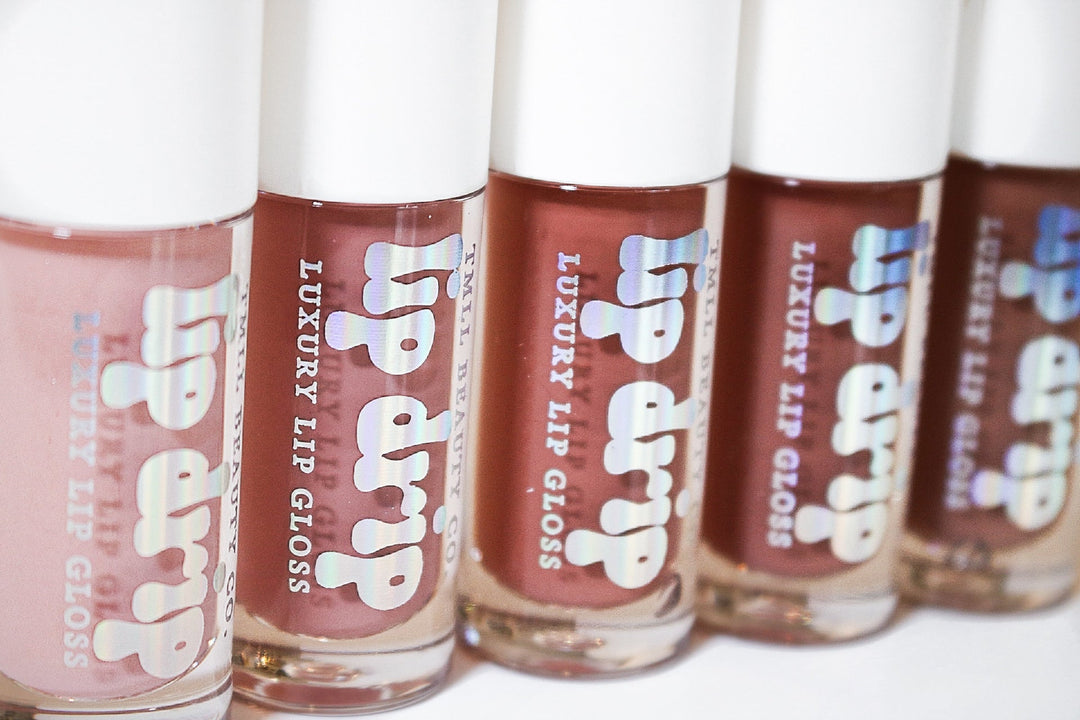 Five Lip Drip Luxury Lip Gloss tubes in nude pink to deep brown shades displayed in a row on a white background

