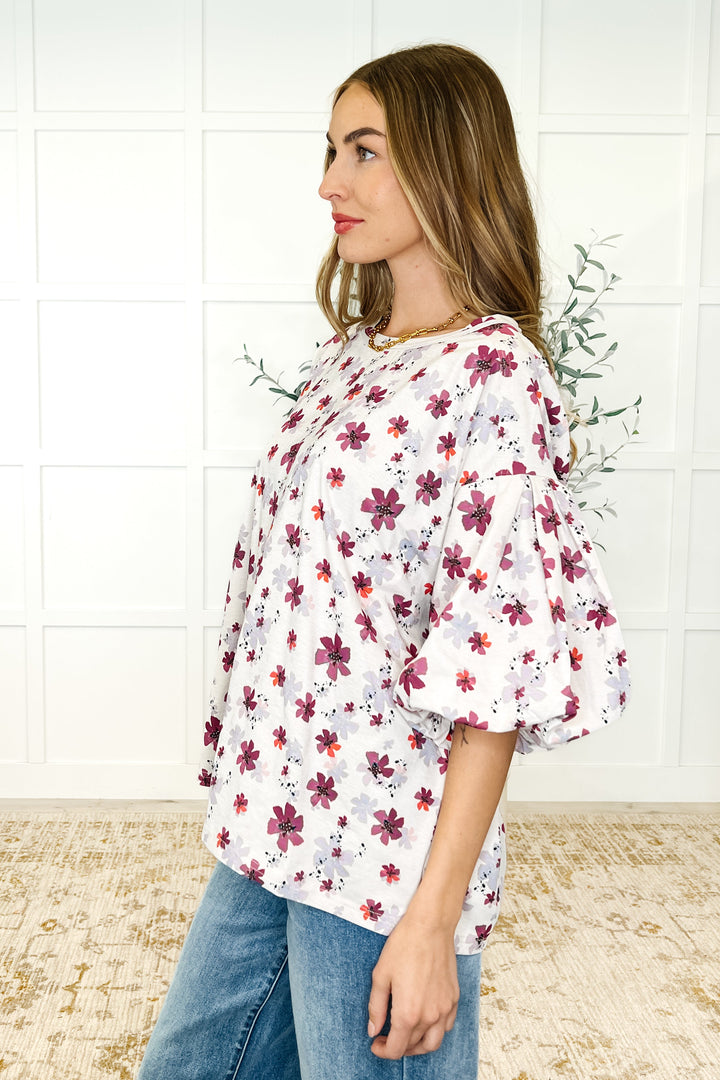 Side view — white floral puff-sleeve babydoll top with magenta flowers, paired with wide-leg jeans
