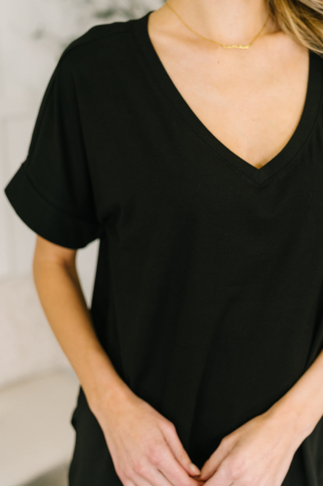 Close-up of the black V-neck tee's neckline with a gold chain necklace