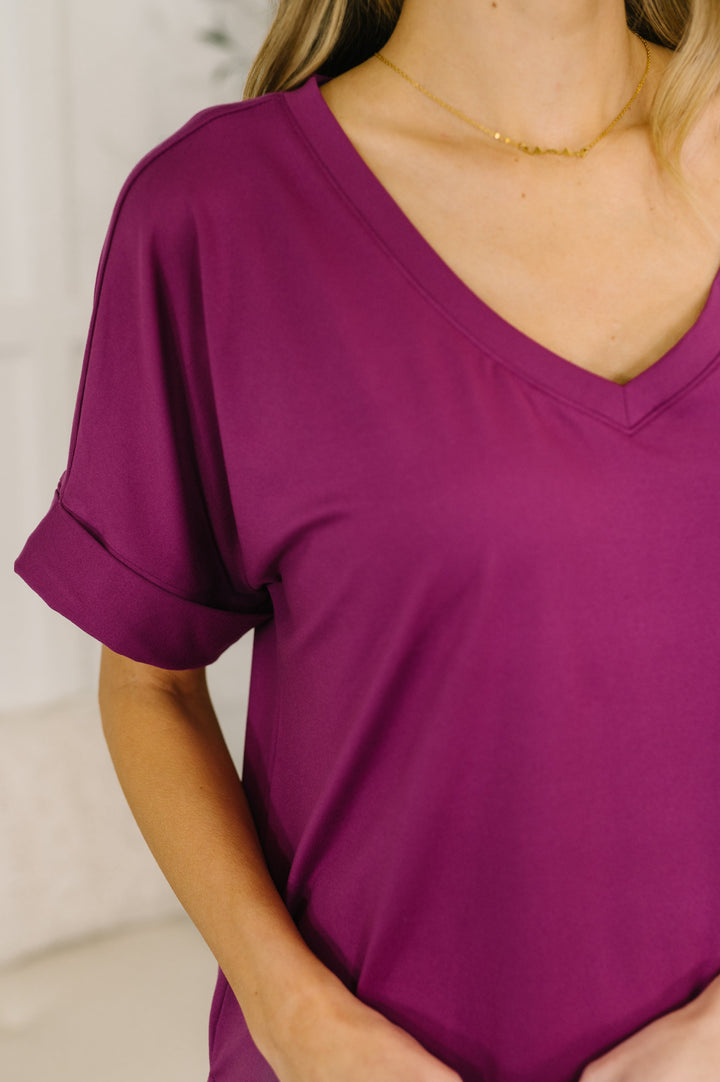 Close-up of the light plum V-neck neckline with cuffed sleeves and gold chain necklace