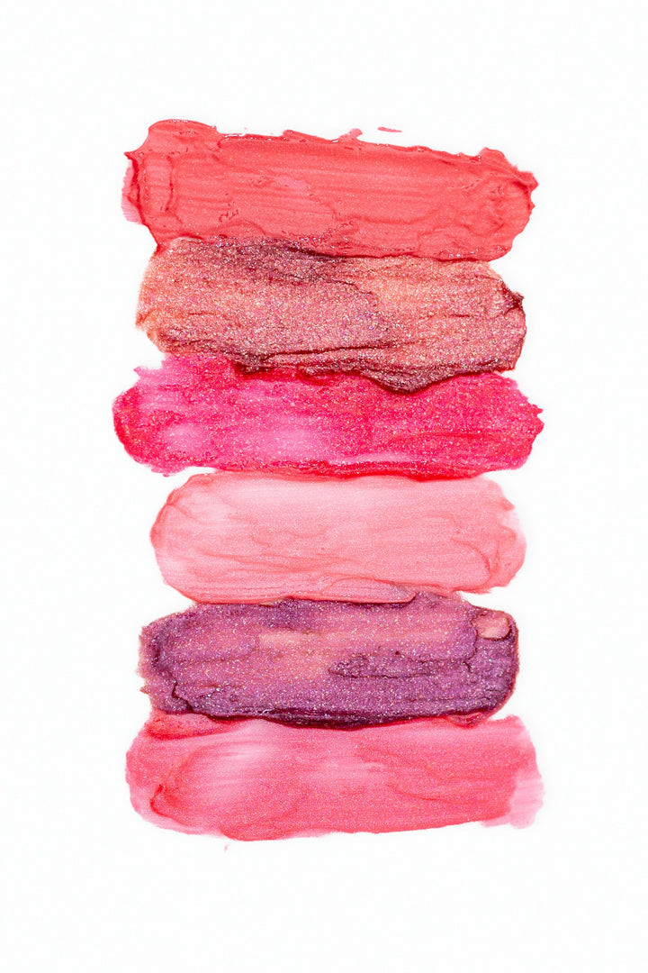 Beaut. Lip Gloss'd color swatches in six shades — coral red, rose gold glitter, hot pink, blush, purple glitter, and pink — stacked on white background