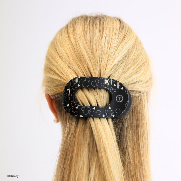 Disney x Teleties Disney Spotlight medium flat round hair clip in black with allover white Mickey silhouette outline print securing a low ponytail on blonde hair against white background