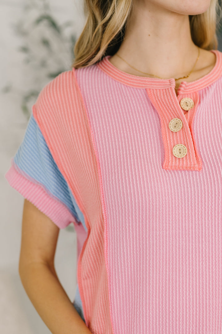 Close-up of a pink and blue color block ribbed henley top with button placket detail