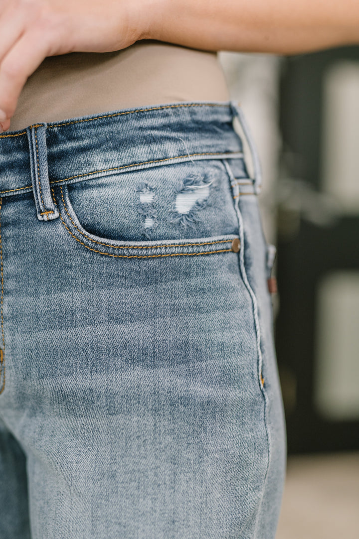 Close-up of light wash straight-leg jeans showing frayed distressing detail at front coin pocket area in regular size
