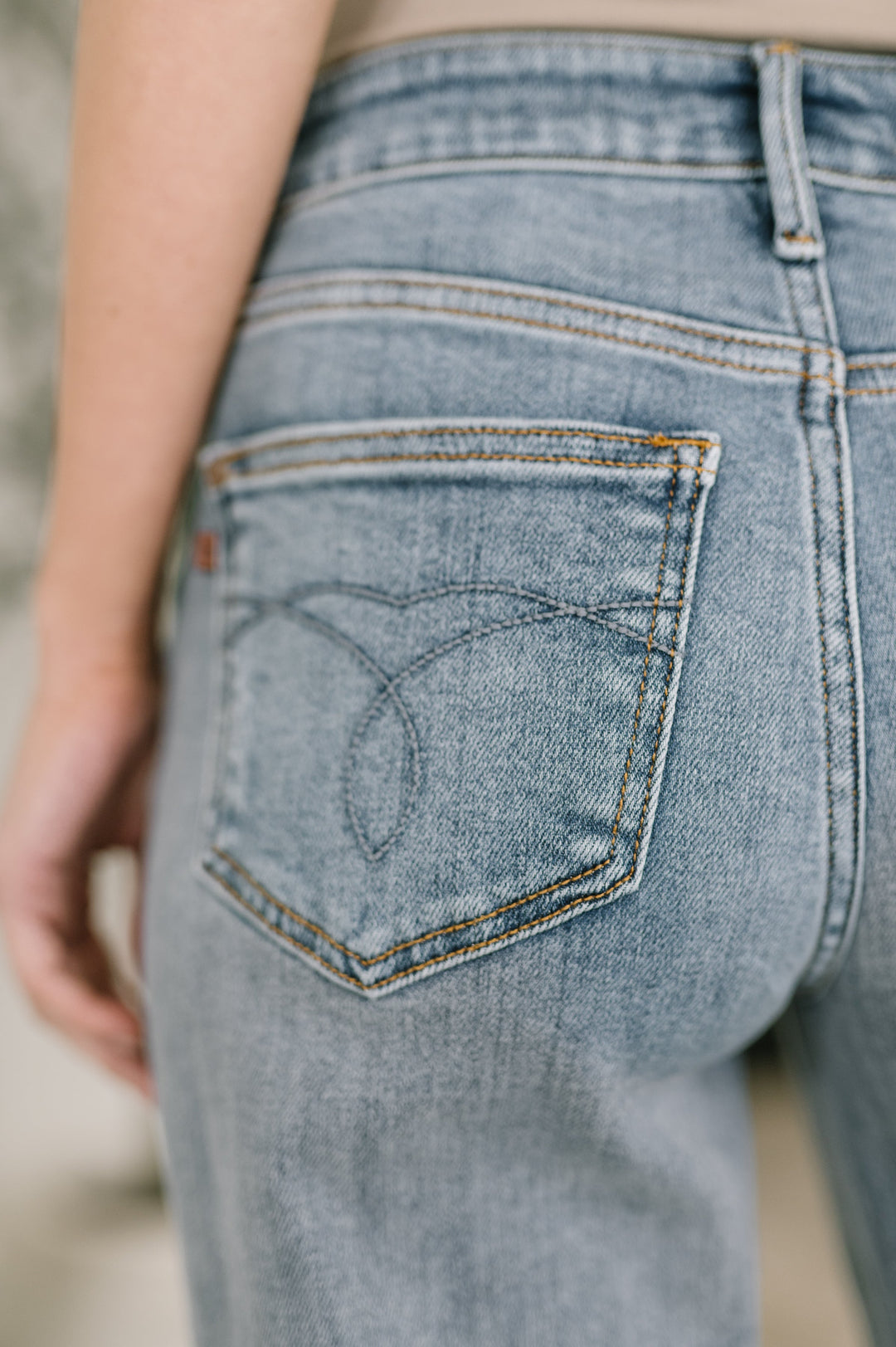 Close-up of light wash straight-leg jeans showing heart-stitched back pocket detail with gold topstitching in regular size
