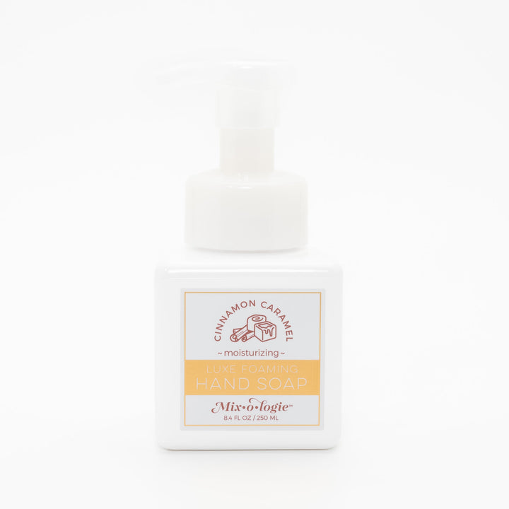 Mixologie Luxe Foaming Hand Soap in Cinnamon Caramel, 8.4 fl oz, white square pump bottle with gold-bordered label and brown cinnamon roll and caramel cube illustration on white background
