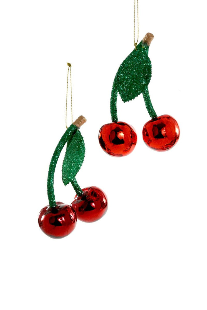 Two red cherry ornaments with green stems on a white background