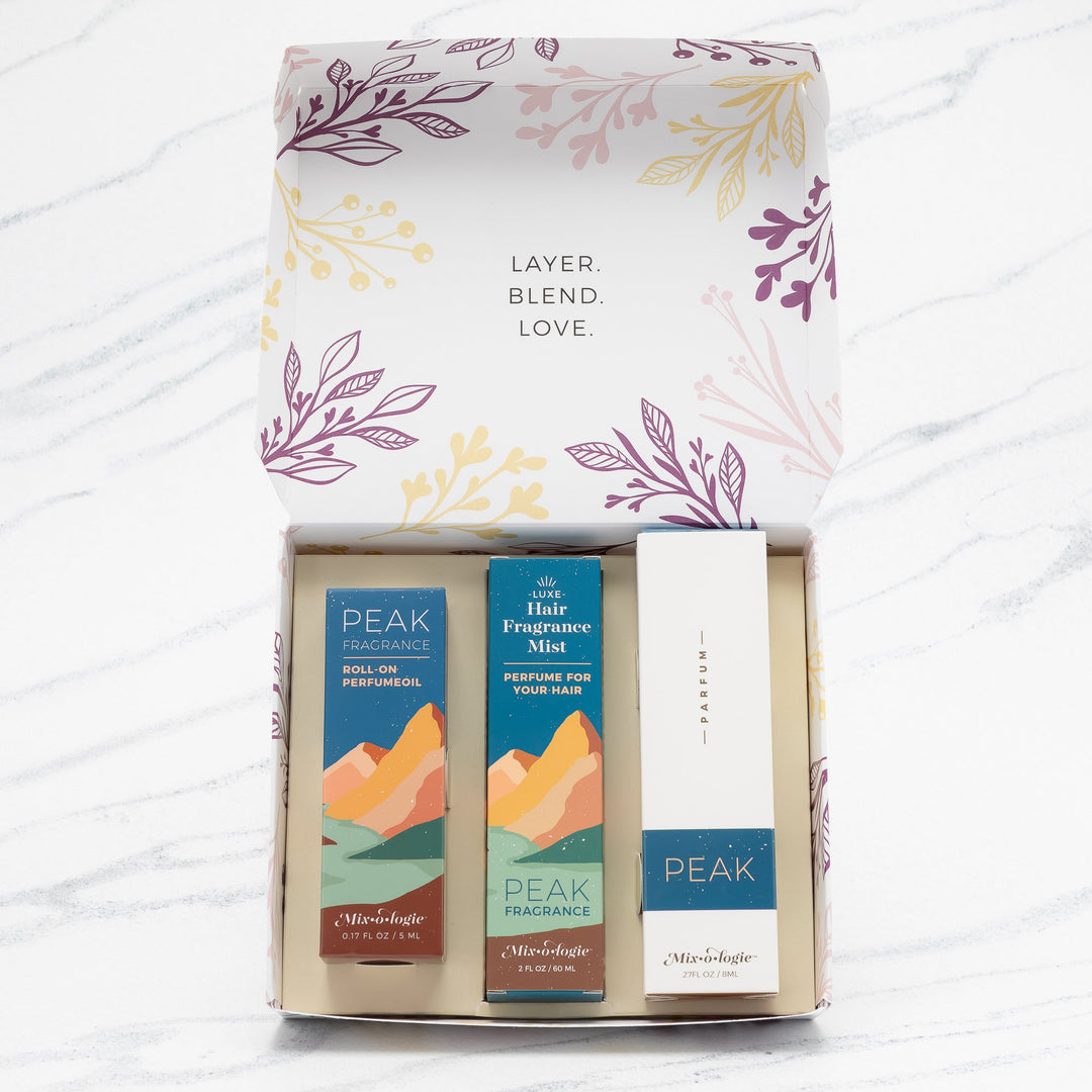 Mixologie Party of Three Gift Set in Peak open box showing parfum spray, Luxe Hair Fragrance Mist, and roll-on perfume oil in teal mountain landscape packaging