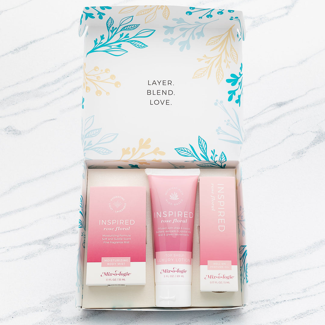 Mixologie Inspired Rose Floral gift set trio open box showing Moisturizing Body Mist, Top Shelf Luxury Lotion, and Roll-On Perfume Oil in blush pink gradient packaging