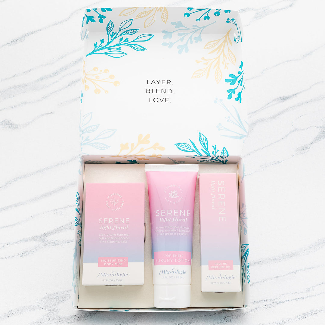 Mixologie Serene Light Floral gift set trio open box showing Moisturizing Body Mist, Top Shelf Luxury Lotion, and Roll-On Perfume Oil in pink to lavender gradient packaging