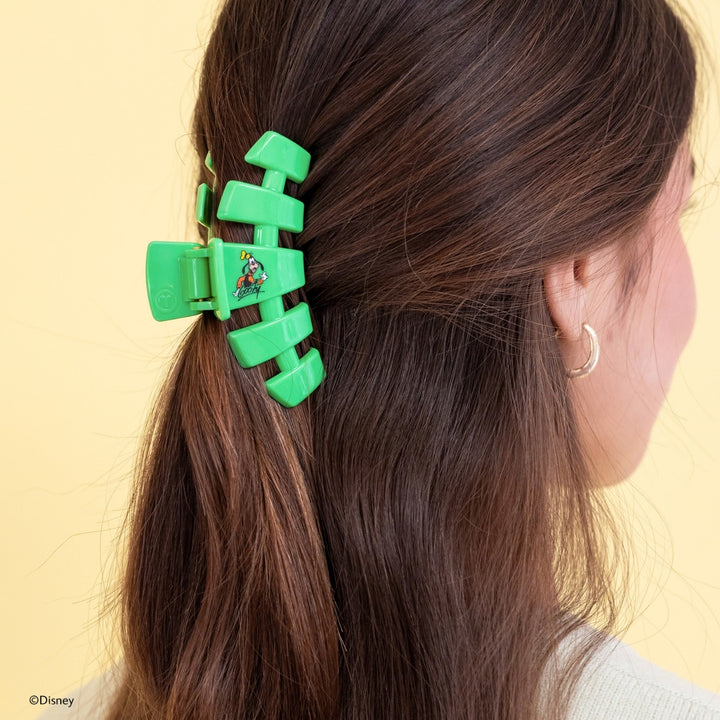 Disney x Teleties Goofy medium hair claw clip in green worn in low ponytail hairstyle against yellow background

