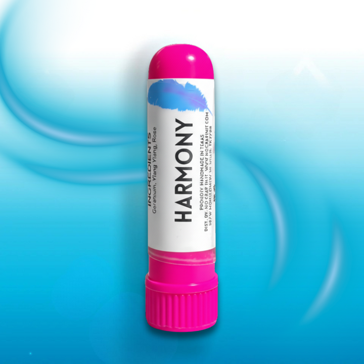 No Crap In It Harmony essential inhaler with hot pink cap, made with geranium, ylang ylang, and rose, standing upright on a light blue swirled background.
