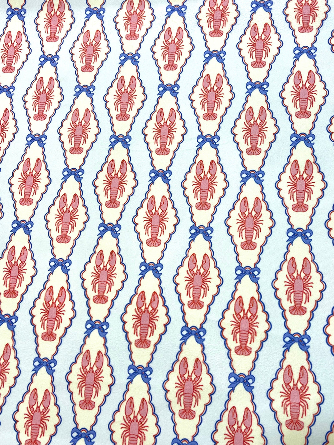 Pink and blue lobster cameo print fabric with scalloped oval frames and blue bow details on light blue background