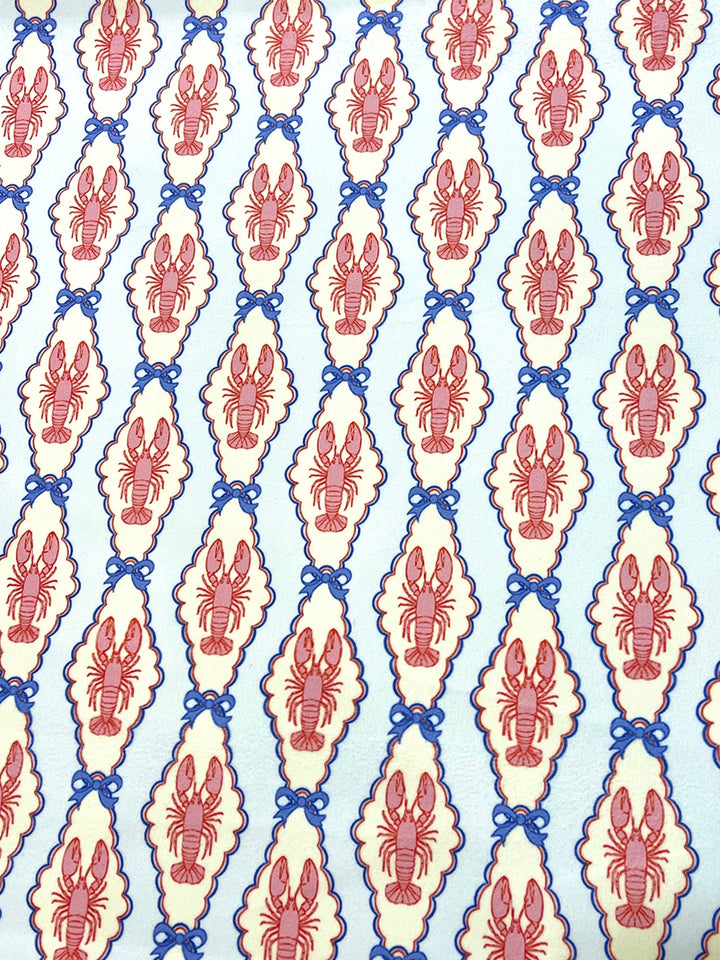 Pink and blue lobster cameo print fabric with scalloped oval frames and blue bow details on light blue background