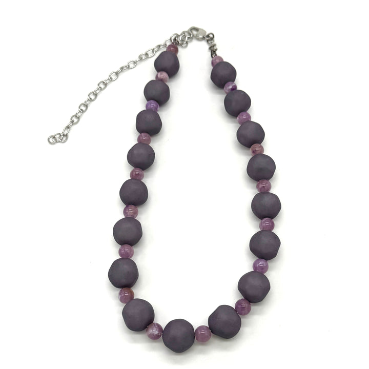Adjustable necklace featuring dark gray and lilac lucite beads laid on a white background.