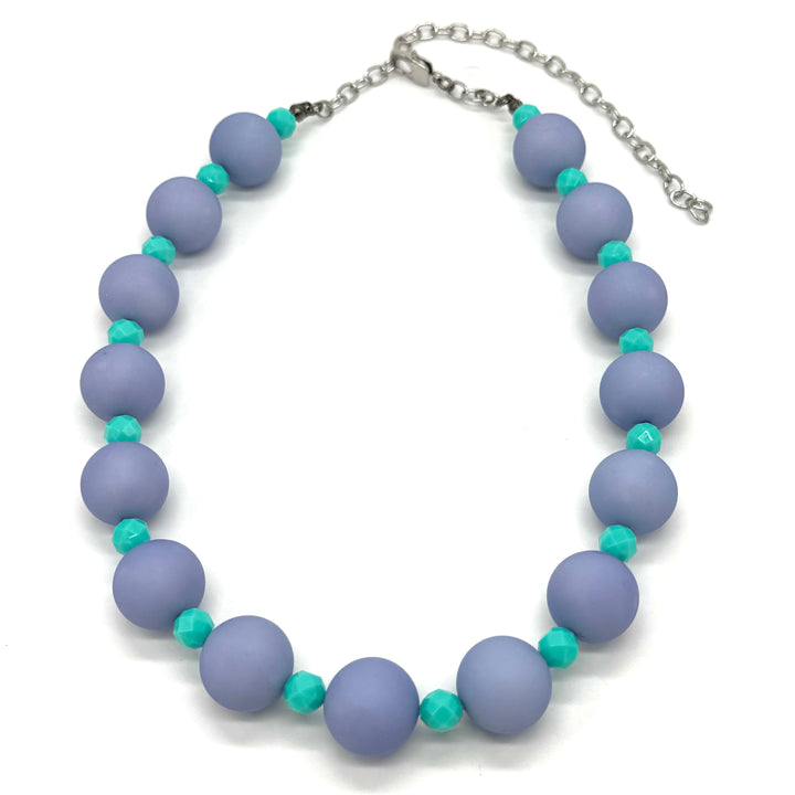 Adjustable necklace featuring chunky periwinkle lucite beads and smaller faceted turquoise spacers on a white background.