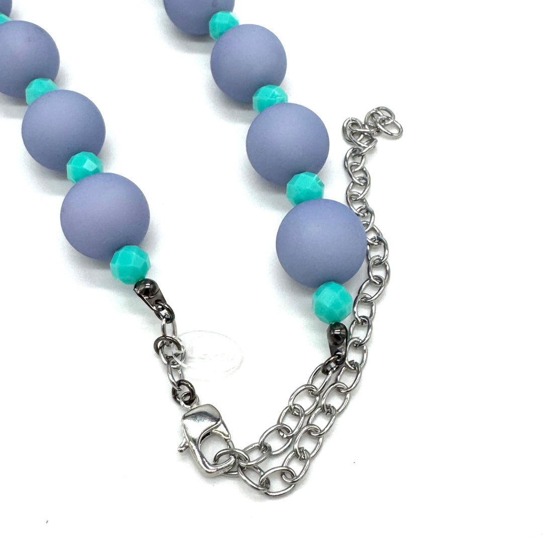 Closeup of adjustable necklace featuring chunky periwinkle lucite beads and smaller faceted turquoise spacers on a white background.