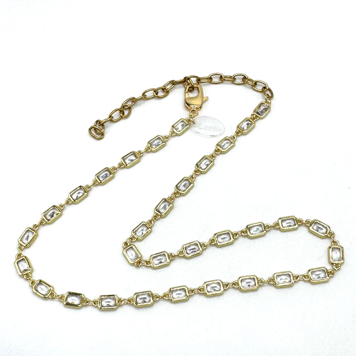 Gold chain necklace with clear stones on a white background