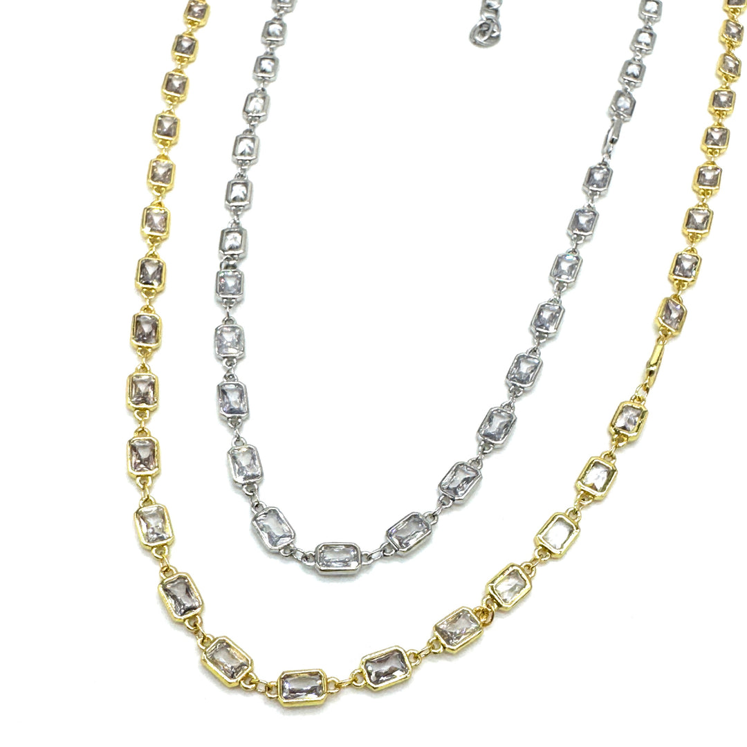 Two gold and silver necklaces with diamond-like stones on a white background