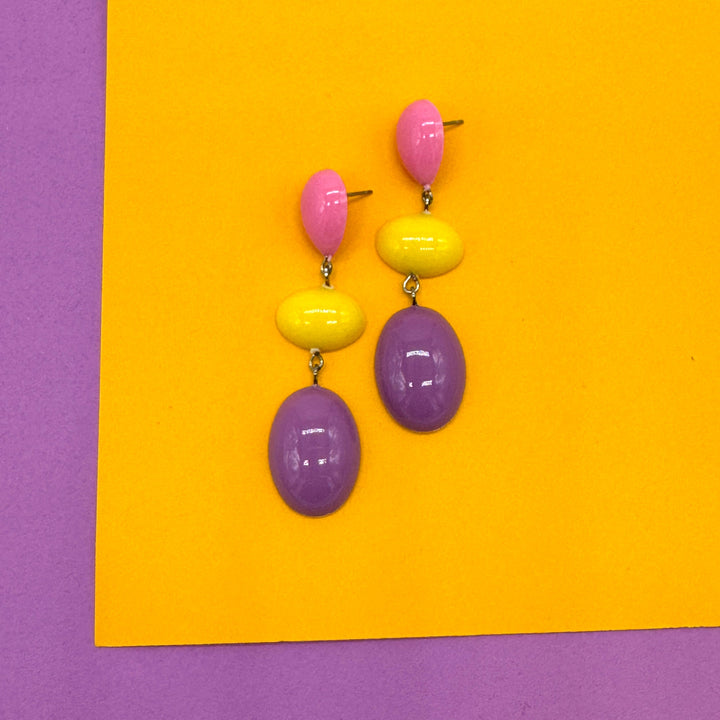 Colorful earrings on a yellow and purple background