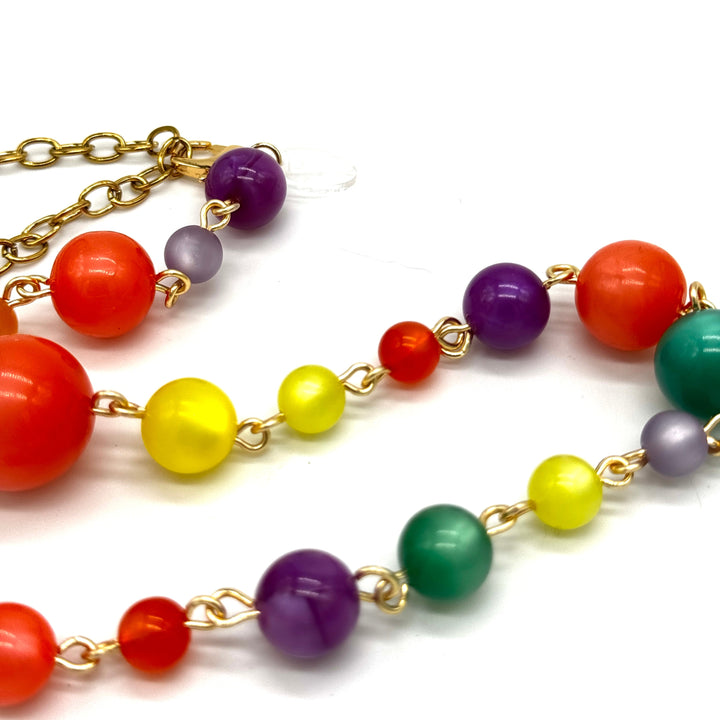 Colorful beaded necklace with gold chain on a white background