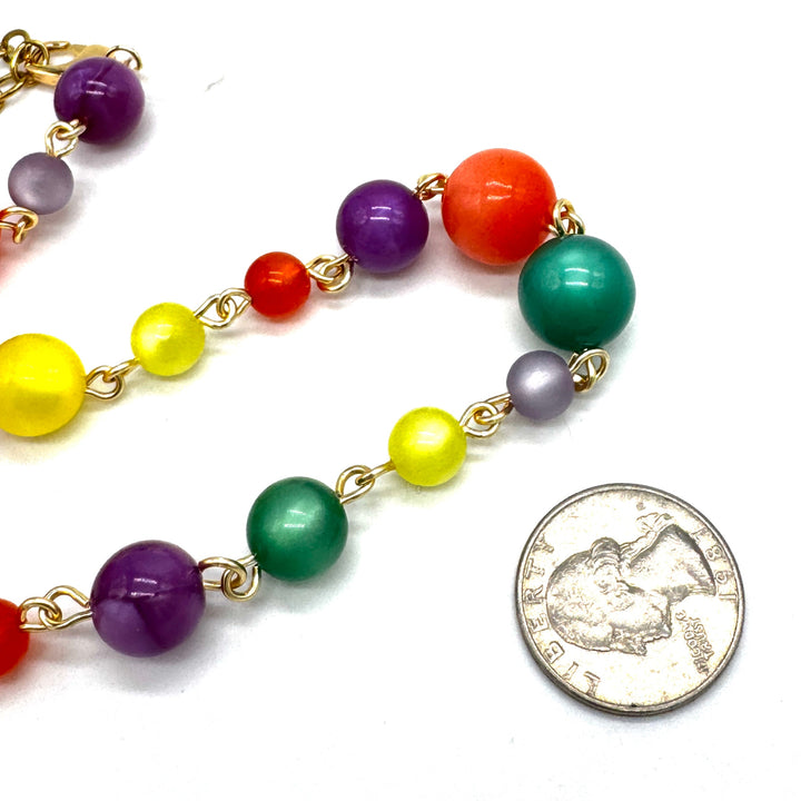 Colorful beaded necklace with a quarter for scale on a white background