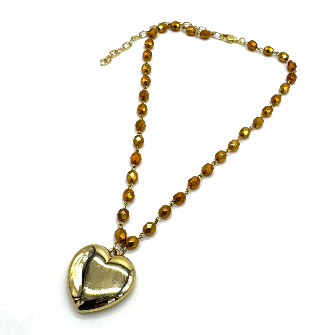 Gold heart-shaped pendant on a chain with gold beads against a white background