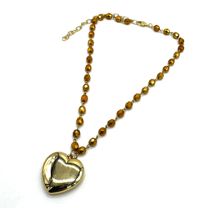 Gold heart-shaped pendant on a chain with gold beads against a white background