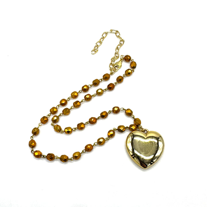 Gold necklace with a heart-shaped pendant on a white background