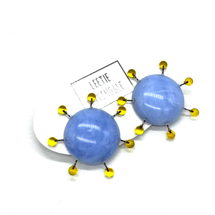 Blue spherical earrings with yellow accents on a white background