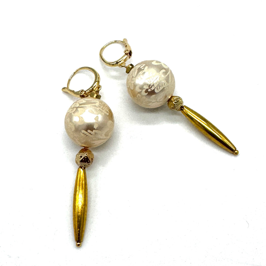 Dangle earrings with floral cream colored beads and golden accents on a white background.