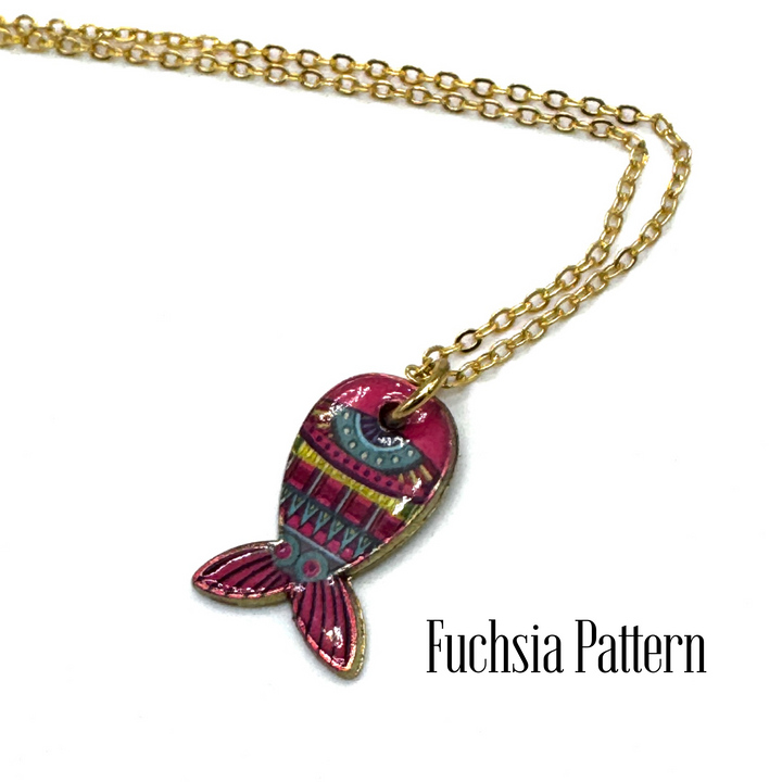 A gold chain necklace with a fish-shaped pendant featuring a vibrant fuchsia and pink pattern, shown on a white background with the text 'Fuchsia Pattern' in the lower right.
