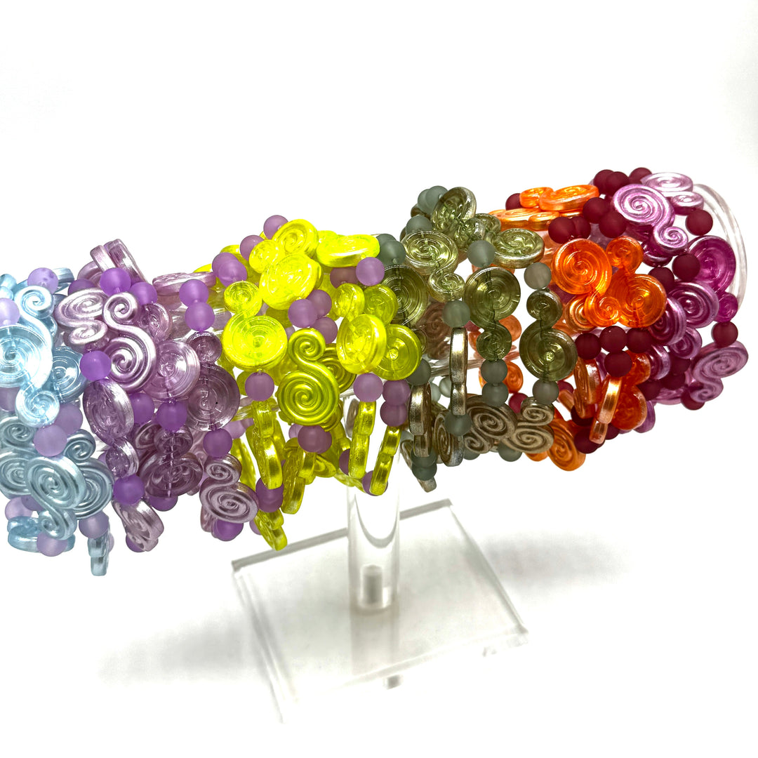 A set of translucent spiral and bead bracelets displayed on a clear acrylic stand against a white background.